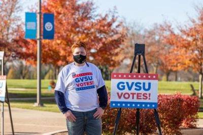 Student standing in front of a GVSU Votes sign